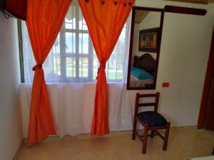 a room with a window with an orange curtain and a chair at Hospedaje Villa Isabel in Aquitania