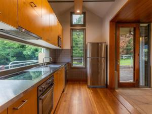uma cozinha com armários de madeira e um frigorífico de aço inoxidável em The Dairy at Cavan I Kangaroo Valley I Stunning Views em Barrengarry