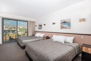 a hotel room with two beds and a balcony at Macquarie 4 Star in Warners Bay