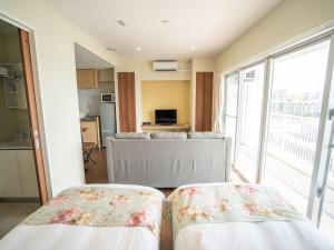 two beds in a room with a kitchen and a living room at Seaside Condominium Rana Chatan in Chatan