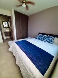 a bedroom with a large bed with a blue blanket at DEPARTAMENTO TOTALMENTE NUEVO, AMOBLADO Y DE LUJO EN TONSUPA in Tonsupa