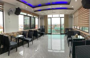 un restaurante con mesas, sillas y ventanas en MV Hotel en Hai Phong