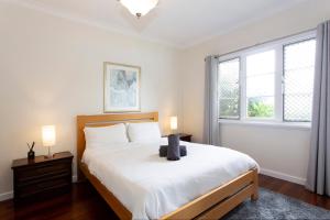 a bedroom with a bed with white sheets and two windows at Cosy Cottage -3 Bedrooms Victoria Park in Perth