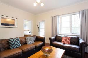 a living room with two leather couches and a table at Cosy Cottage -3 Bedrooms Victoria Park in Perth