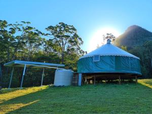 Noosa Eco Retreat في Pomona: خيمة زرقاء كبيرة بجانبها مبنى