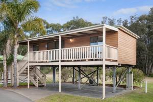 a house with a wrap around deck with palm trees at Discovery Parks - Eden in Eden