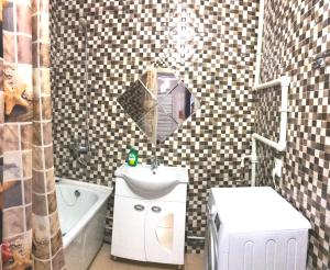 een badkamer met een wastafel, een toilet en een spiegel bij Апартаменты в центре OrenRoom56 in Orenburg