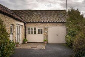 een garage met twee witte garagedeuren op een huis bij Ford End Cottage in York