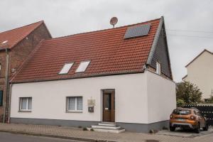 ein weißes Haus mit rotem Dach und einem Auto in der Unterkunft Apartment Haus 8 Hohenwarsleben in Hohenwarsleben