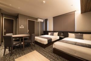 a hotel room with two beds and a table at ENISIA BASE Kagonma in Kagoshima