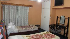 a bedroom with two beds and a desk and a window at Flintstones Backpackers in Lusaka