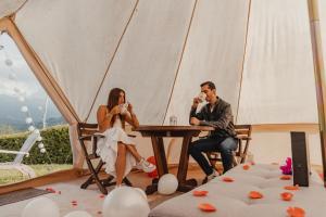 Ein Mann und eine Frau sitzen an einem Tisch in einem Zelt. in der Unterkunft Montana Glamping Salento in Salento