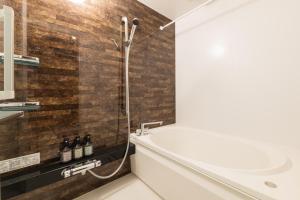 a bathroom with a shower and a tub and a sink at ENISIA BASE Kagonma in Kagoshima