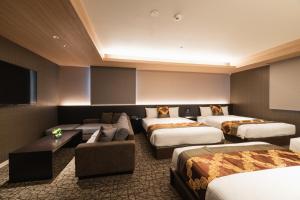 a hotel room with four beds and a flat screen tv at GRAND BASE Kagoshima in Kagoshima