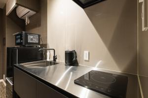 eine kleine Küche mit einer Spüle und einer Mikrowelle in der Unterkunft GRAND BASE Kagoshima in Kagoshima