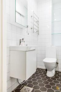 a white bathroom with a sink and a toilet at Pieni Roobertinkatu Big 13 in Helsinki