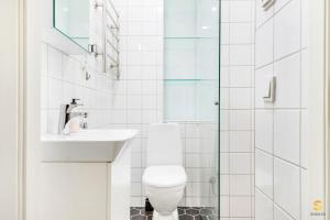 a white bathroom with a toilet and a sink at Pieni Roobertinkatu Big 13 in Helsinki