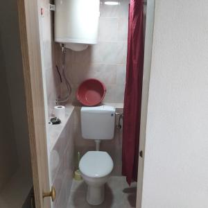 a small bathroom with a toilet and a red shower curtain at House 23 A3 in Tivat +4 photos