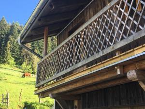 a wooden building with a horse grazing in a field at Ferme des Moines in Pontarlier