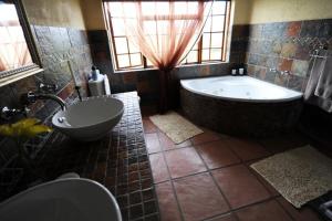 ein großes Badezimmer mit Badewanne und Waschbecken in der Unterkunft Jocks Cottages in Dullstroom