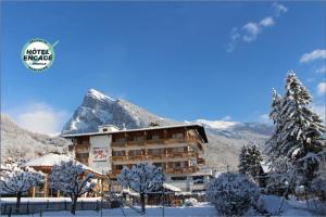 a hotel with a snow covered mountain in the background at Chalet-H&ocirc;tel Neige et Roc, The Originals Relais in Samo&euml;ns