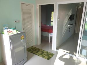 a kitchen with a small refrigerator and a bedroom at Vanilla Ville Resort in Khlong Thom