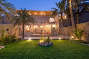 a yard with palm trees and a building with lights at Antique Inn in Nizwa