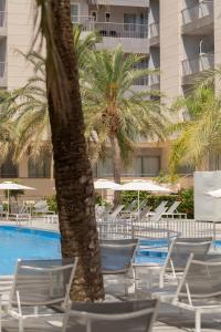 a group of chairs and palm trees next to a swimming pool at Bordoy Cosmopolitan in Playa de Palma