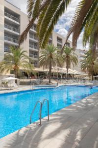 帕爾馬海灘的住宿－Bordoy Cosmopolitan，一座大型游泳池,在一座建筑前种有棕榈树