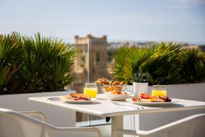 a table with plates of food and glasses of orange juice at be.HOTEL in St. Julianʼs