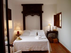 a bedroom with a white bed with a wooden headboard at Cortijo Los Malenos in Agua Amarga