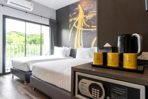 a hotel room with two beds and a microwave at Sleep Mai Chiang Mai Airport Lifestyle Hotel - SHA Plus in Chiang Mai