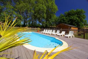 une piscine avec des chaises blanches et une terrasse en bois dans l'établissement Domaine de Garille, à Aragon
