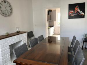 a dining room with a table and a clock on the wall at Gîte Manava - grande maison avec jardin en centre ville in Valognes +8 photos