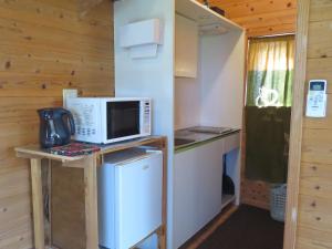 uma pequena cozinha com um micro-ondas e um frigorífico em Cottage Orange House Yakushima em Yakushima