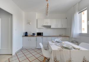 Una cocina blanca con una mesa y sillas blancas. en Fauriel Aimé, en Saint-Étienne