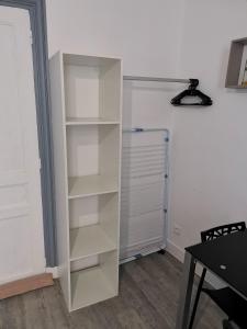 een witte boekenplank in een kamer met een koelkast bij Studio Le Nougat in Montélimar