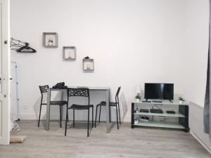 a dining room with a table and chairs and a television at Studio Le Nougat in Montélimar
