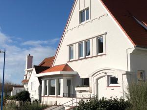 een wit huis met een rood dak bij Zeeparel XL in Koksijde