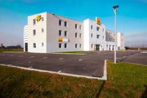 un gran edificio blanco con un cartel en un estacionamiento en Premiere Classe Caen Nord - Mémorial, en Caen