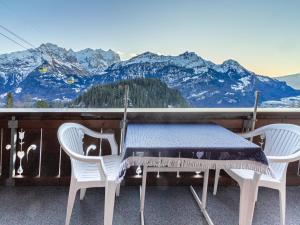 einen Tisch und zwei Stühle auf einem Balkon mit Bergblick in der Unterkunft Ferienwohnung & Studio Schaad in Hasliberg Wasserwendi