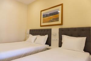 two beds in a hotel room with a picture on the wall at Residencial do Areeiro in Lisbon