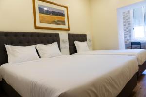 two beds in a hotel room with white sheets at Residencial do Areeiro in Lisbon
