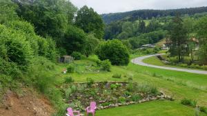 un jardín con sillas rosas y flores en una colina en La mansarde aux digitales en La Croix-aux-Mines