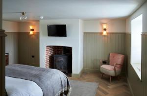 a bedroom with a bed and a chair and a fireplace at The Ingham Swan in Stalham +21 photos