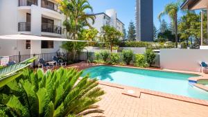 a swimming pool in front of a building with palm trees at Burleigh on the Beach in Gold Coast