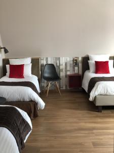 a bedroom with two beds with red pillows and a chair at Hôtel Panorama in Munster