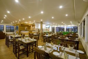 a restaurant with wooden tables and chairs and windows at Vision Safari Pvt Ltd in Sauraha
