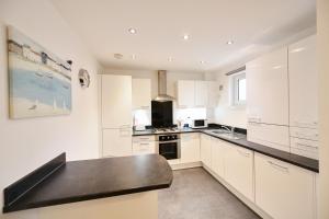 a kitchen with white cabinets and a black counter top at Harbour Quay Apartment in Irvine