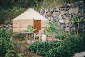 a yurt with a table and chairs in front of a stone wall at Retiro Atlântico in Urzelina